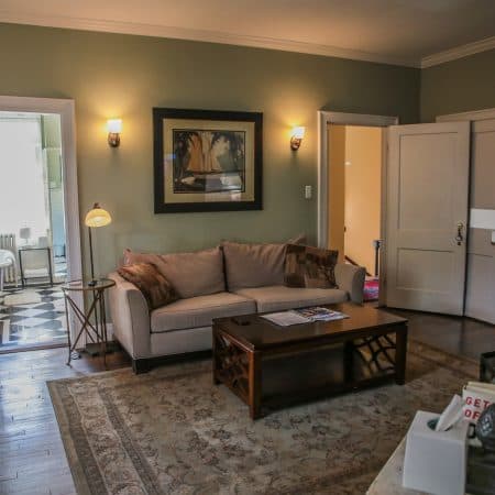 A living room with light green walls, a beige sofa, a wooden coffee table, and an area rug.