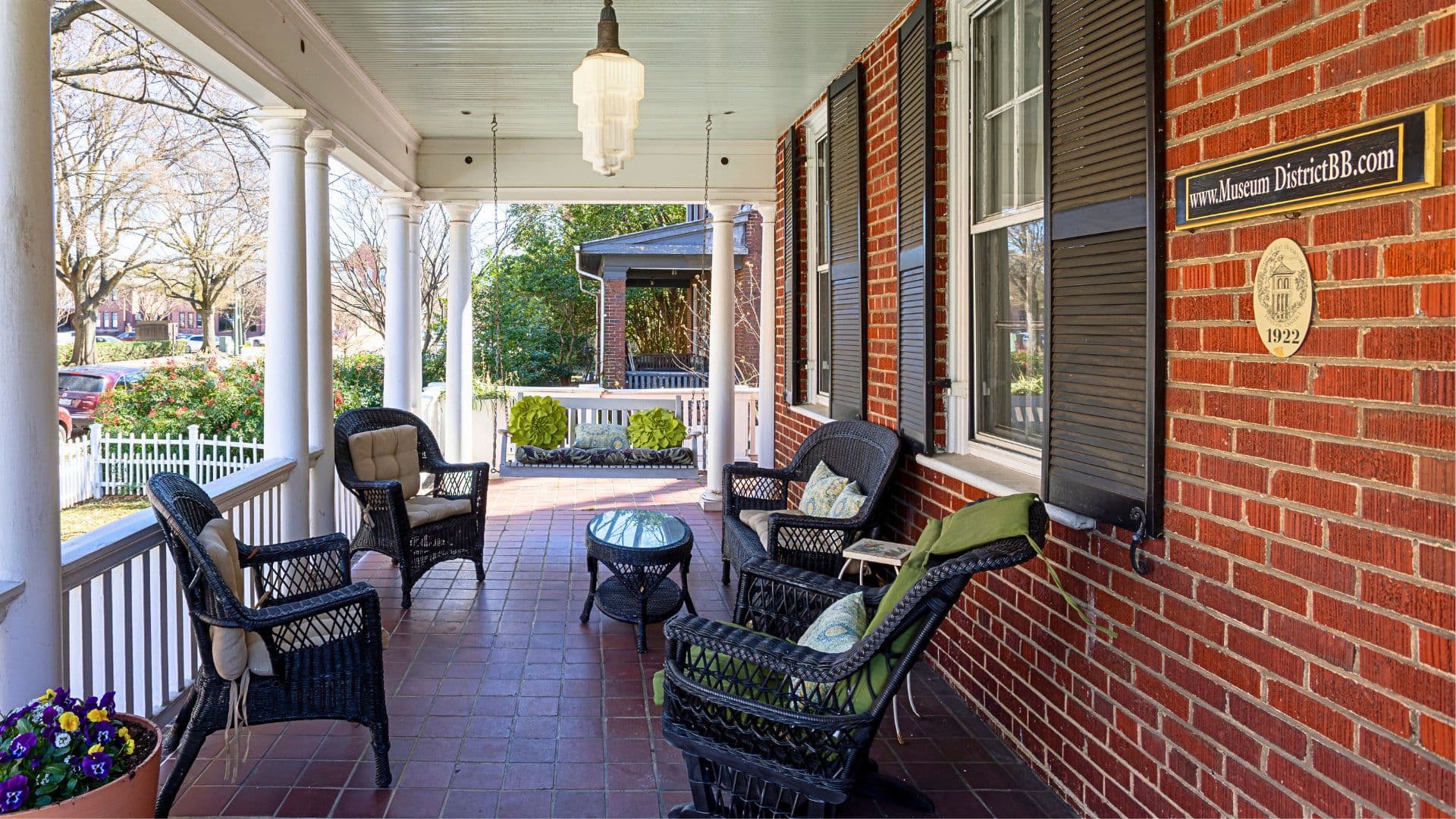 A cozy porch with wicker chairs, a small table, and a view of the garden.