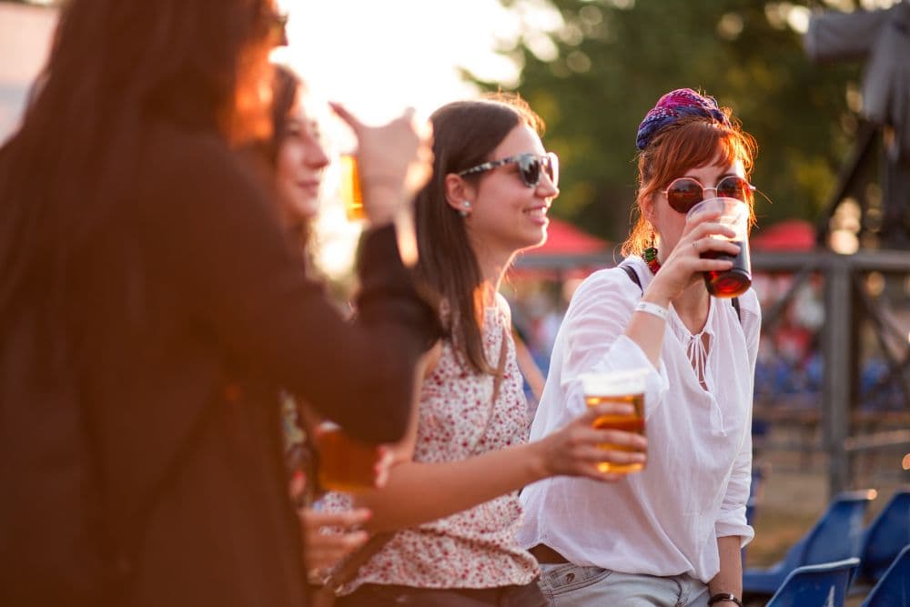 A group of friends enjoying drinks at an outdoor event during sunset.